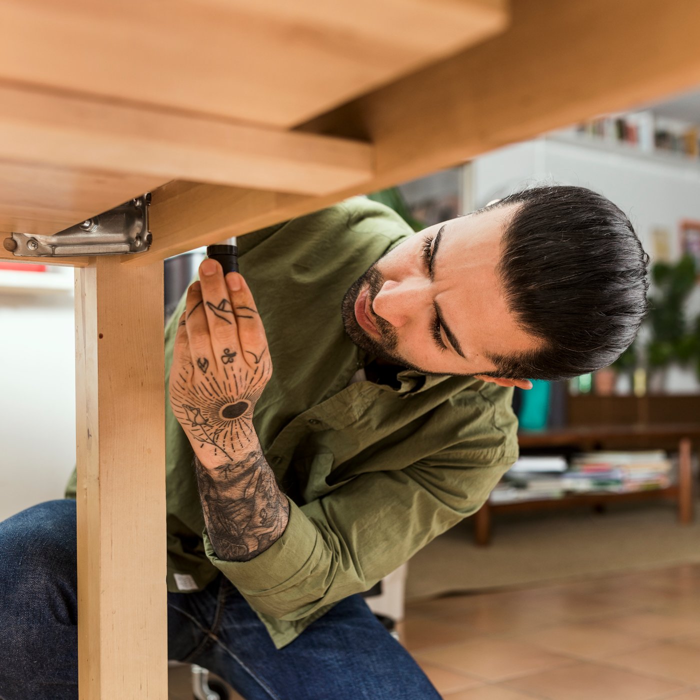 En person sitter på huk för att skruva åt en skruv i en trämöbel.