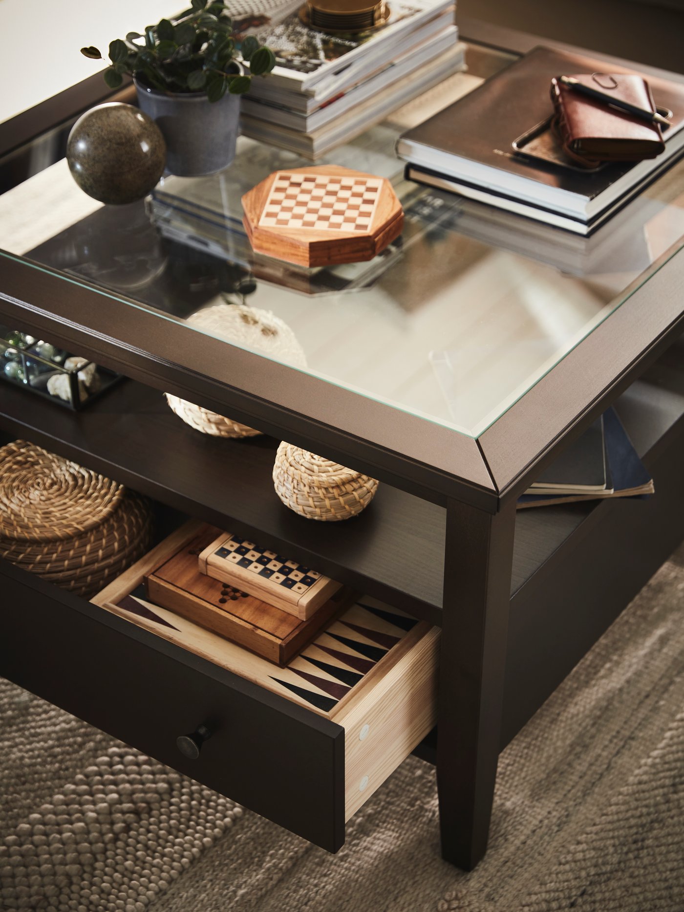 Various objects including books and baskets stand on the top and the shelf and inside the drawer of an IDANÄS coffee table.