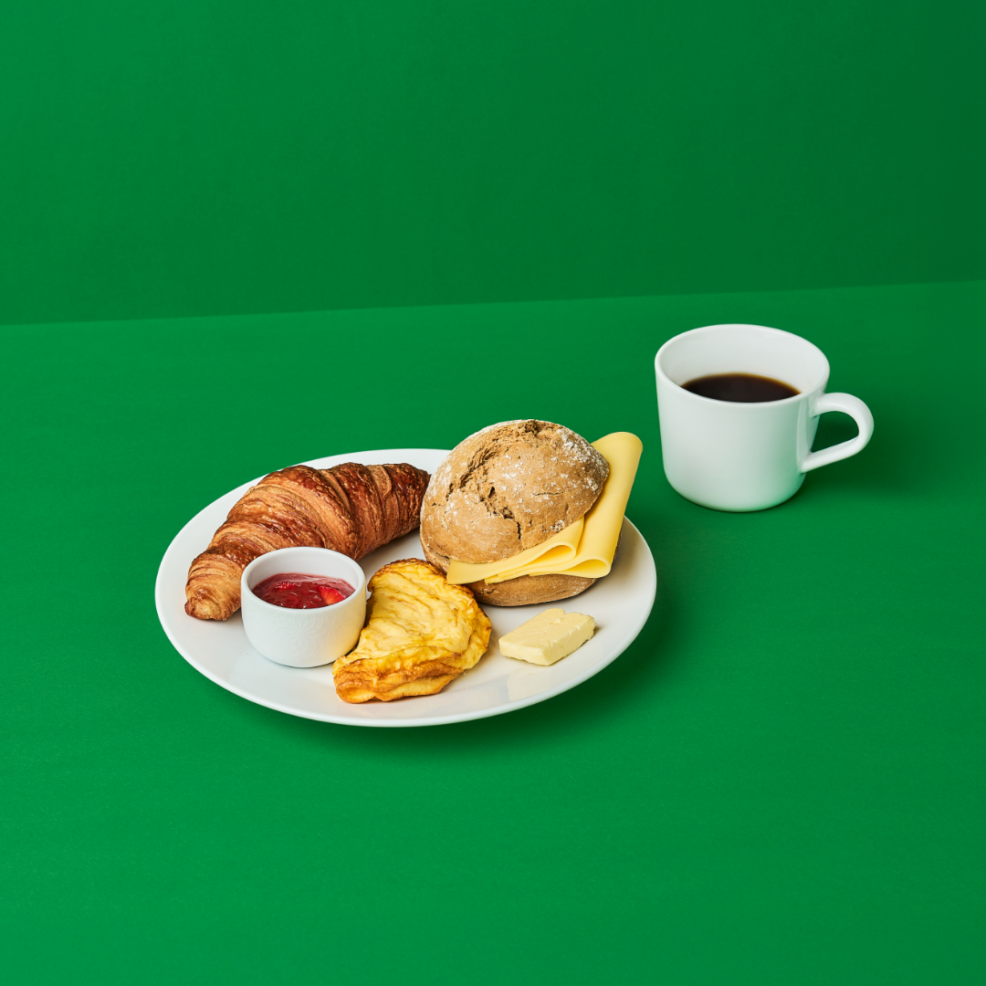 IKEA breakfast consisting of an artisan bread roll, a butter croissant, 2 slices of cheese, an omelet, jam, and butter.