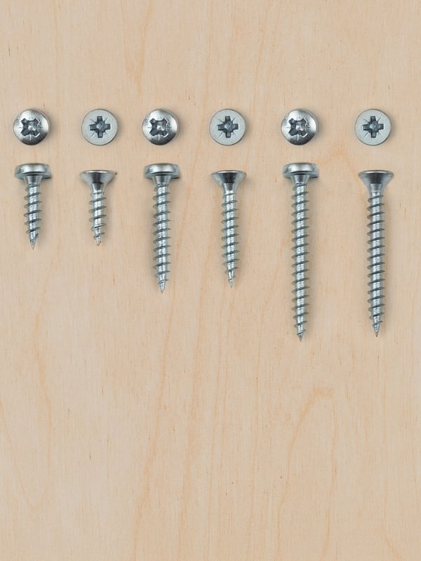 Various sizes of screws on a pine background