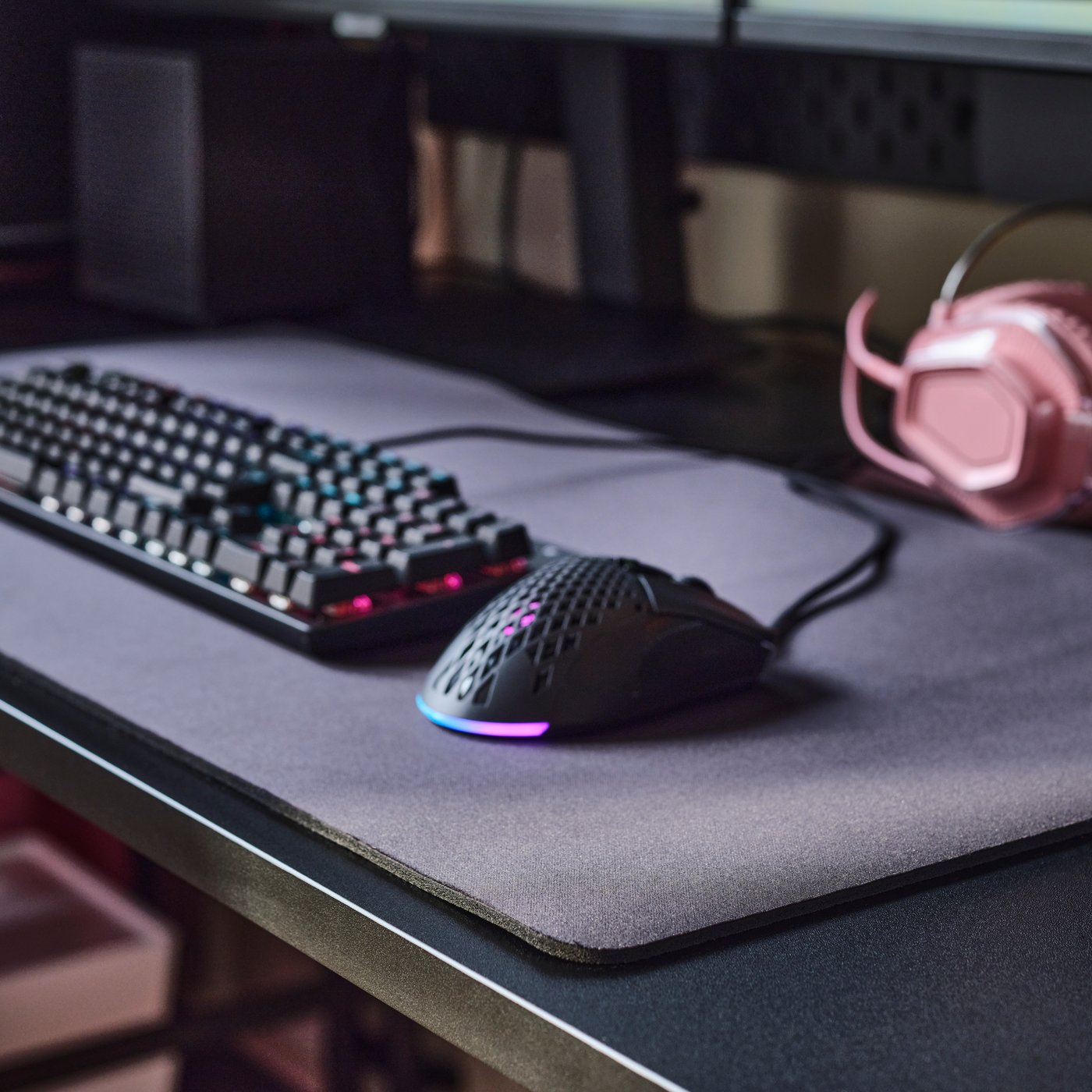 Un teclado y un mouse sobre un tapete para mouse gamer LÅNESPELARE negro, colocados sobre un escritorio gamer FRÖSKELÅS negro.