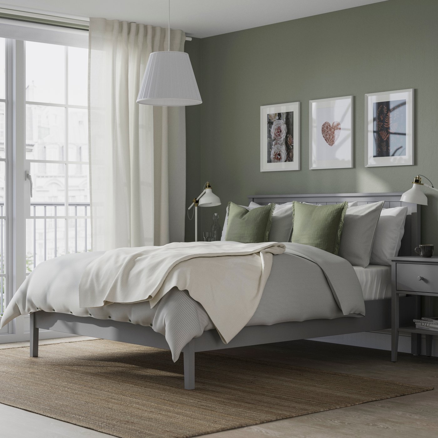 Modern bedroom with gray bed, sage green pillows, white bedding, and framed wall art.