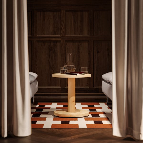 A close-up with two SÖDERHAMN sofas, a pine sidetable in the centre, positioned on a geometric patterned rug.
