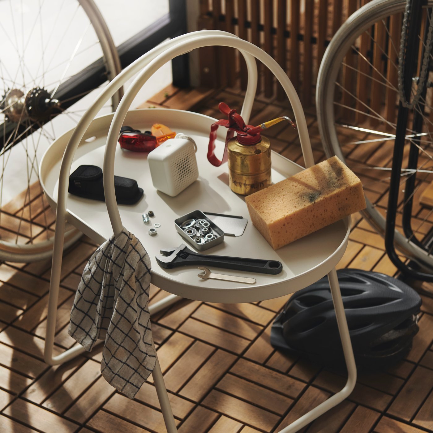 A close-up of a white MÅBÄRSSKÄR coffee table made for outdoor use, displaying hobby items like a sponge and a jar.