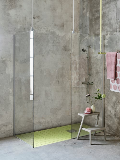 Mit zwei OPPEJEN Duschwänden wurde in einem Badezimmer in grauem Beton eine geräumige ebenerdige Dusche gestaltet.