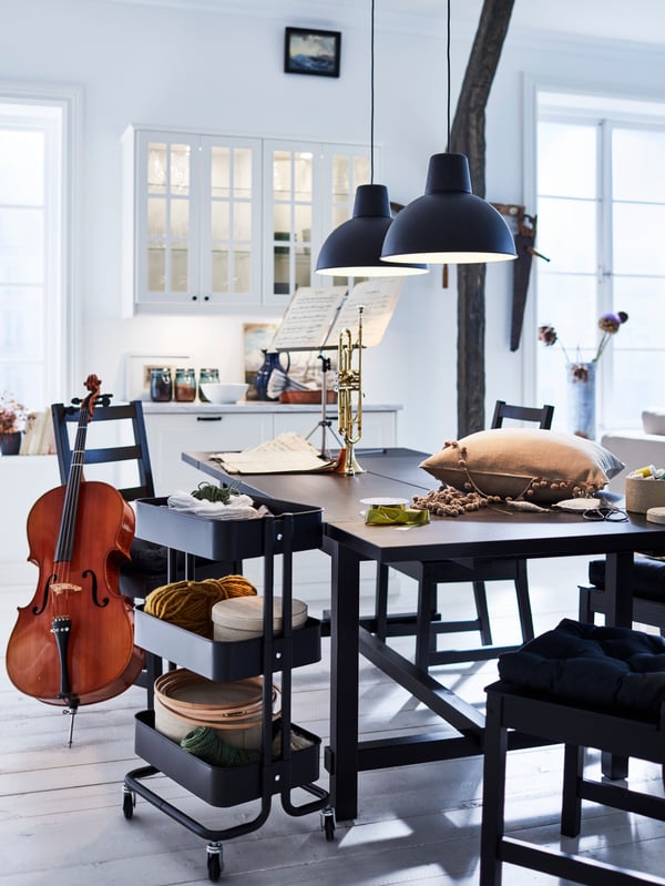A white kitchen with a black extendable table and four black chairs. Musical instruments are on and around the table.