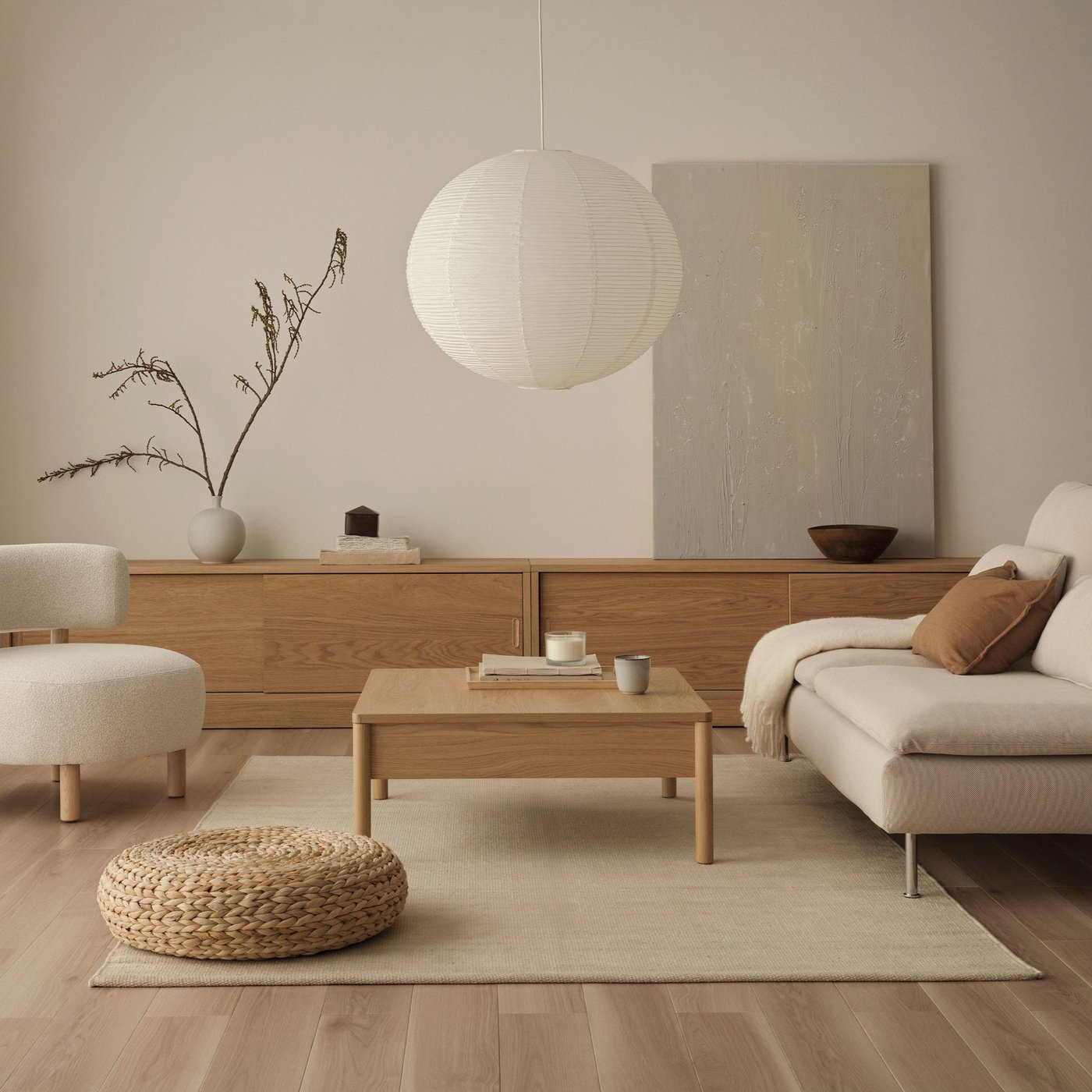 ライトベージュのローソファ。ブラウンのクッションとブランケット、ローテーブルはシンプルな無垢材。