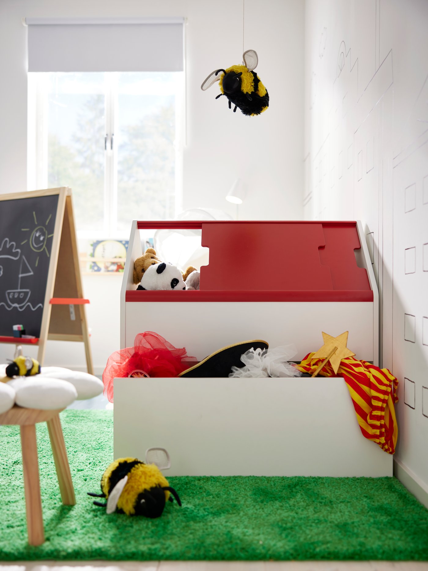VITBJÖRN storage unit with drawer, shaped as a house, standing in the middle of children’s room with toys in and around it.