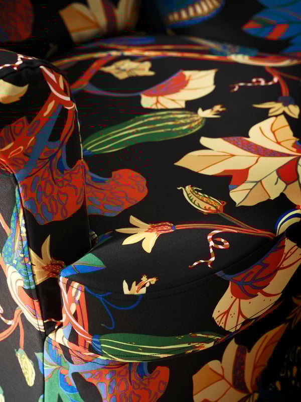 Gros plan sur une housse STRANDMON montrant ses motifs floraux aux couleurs vives, sur un fond noir.
