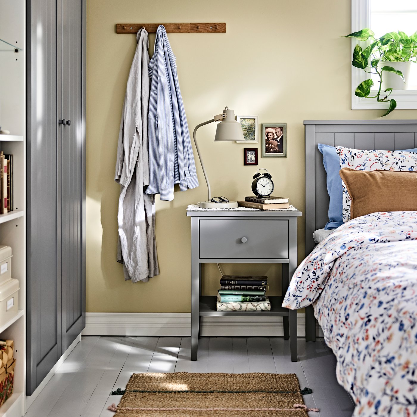 A bedroom corner with a GULLABERG bedside table beside the bed, shown with a lamp, books and small items on its surface.