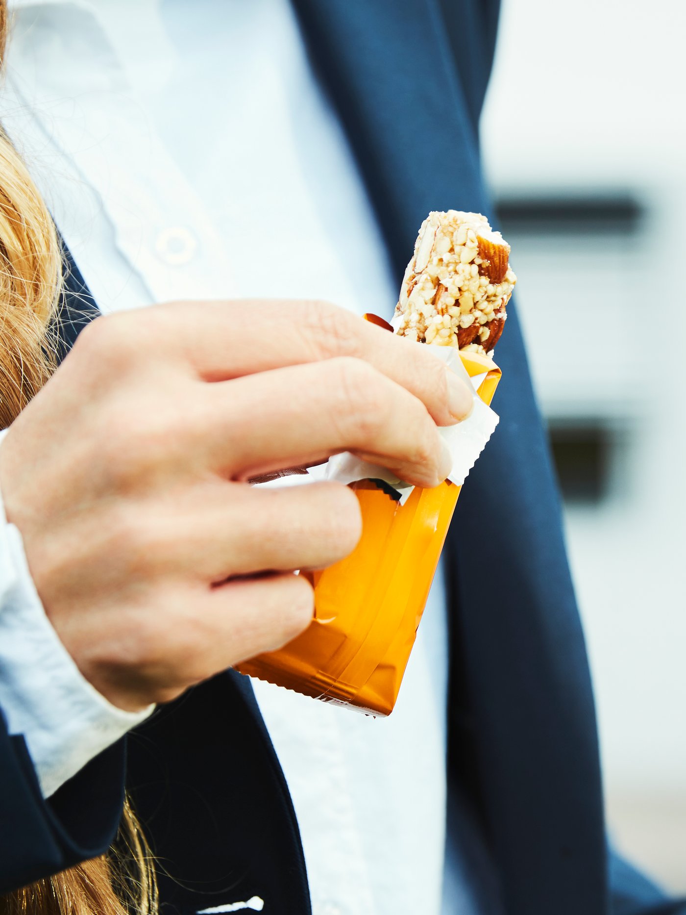 Una persona que lleva una chaqueta azul y una camisa blanca sujeta una barrita energética MUNSBIT con sal marina.