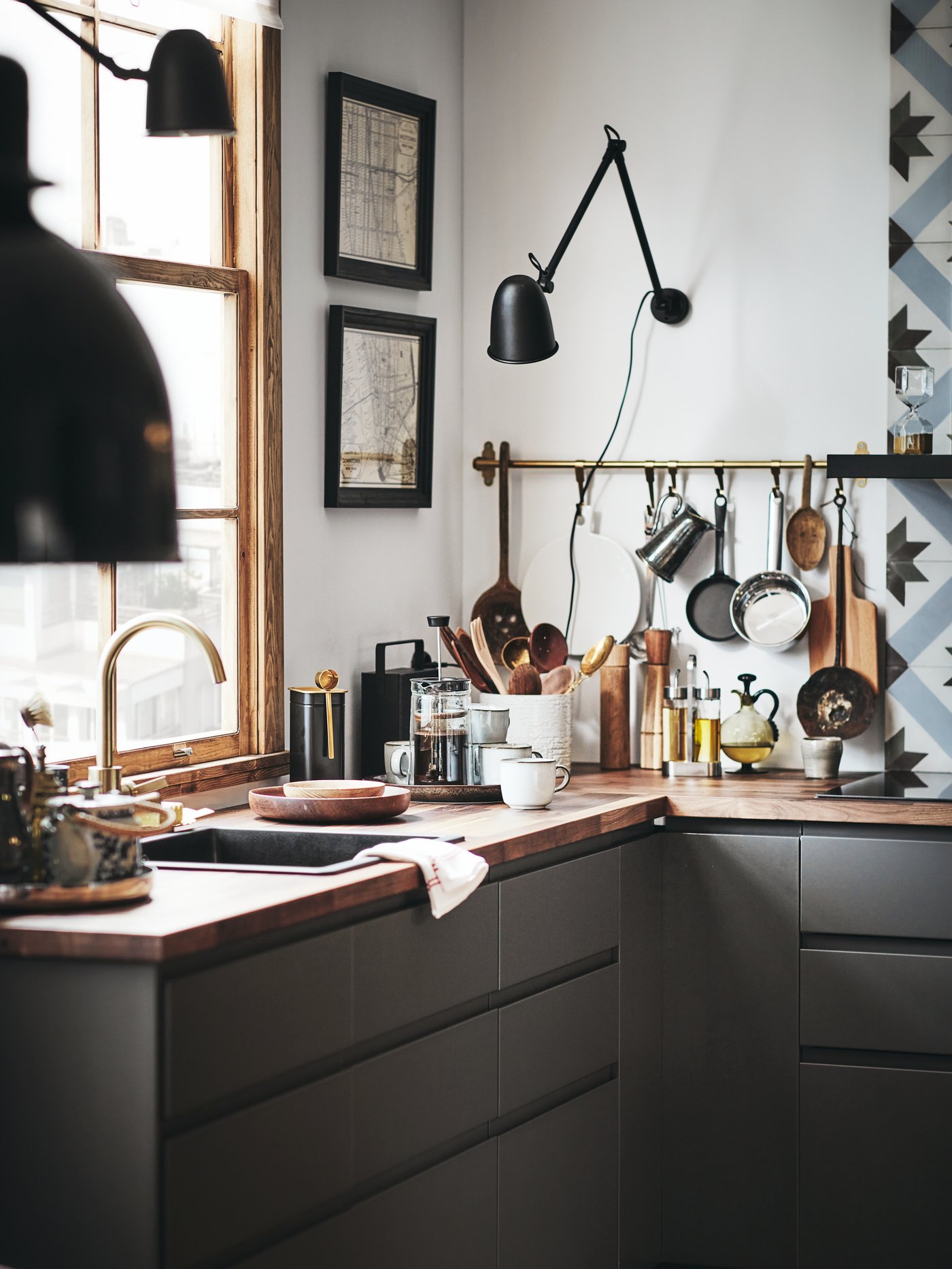A METOD kitchen with a wooden worktop. On the worktop are kitchen utensils, mugs and a coffee pot, with a rail on the wall.