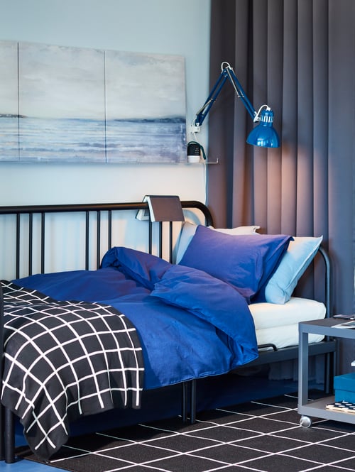 Bedroom featuring a black day bed frame made of steel covered by a quilt cover with pillowcase and a black checkered throw.