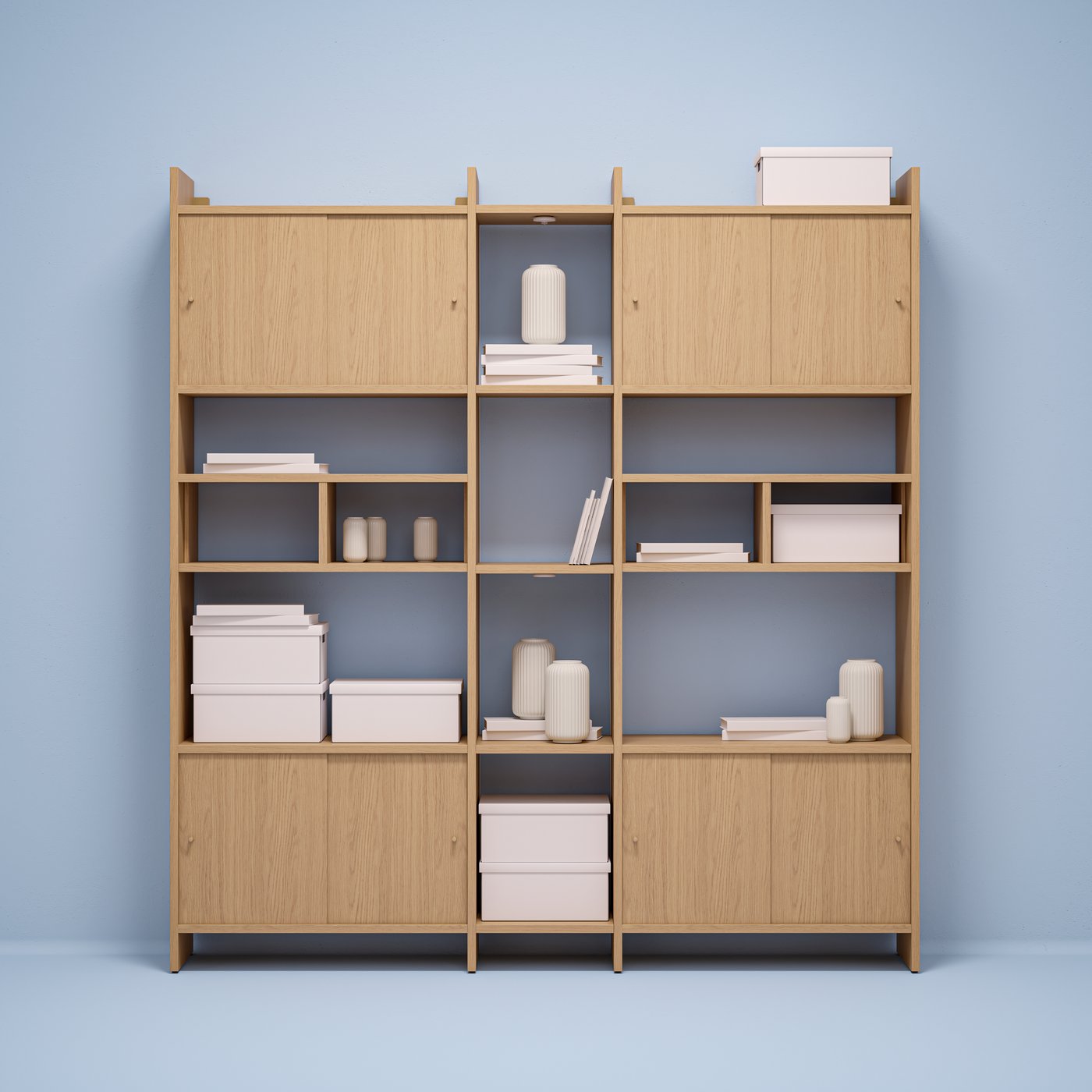 An oak-effect LÅDMAKARE storage combination with sliding-door cabinets and shelving filled with boxes and decoration.