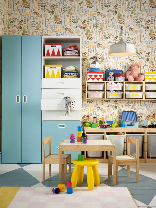 Part of a children’s room showing a tall mirror and pegboards on the wall and below plenty of easy-access pull-out storage.