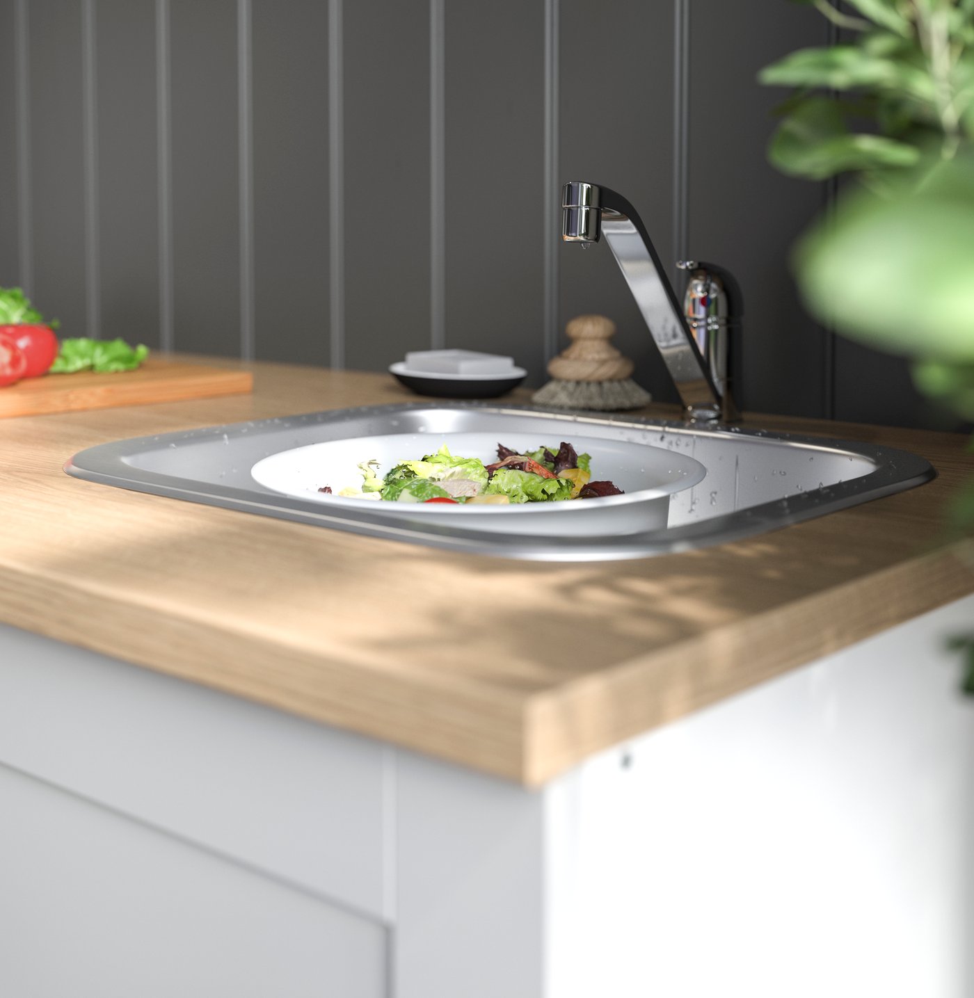 Un mesón de cocina de madera con un pequeño lavaplatos que tiene un colador con verduras adentro.