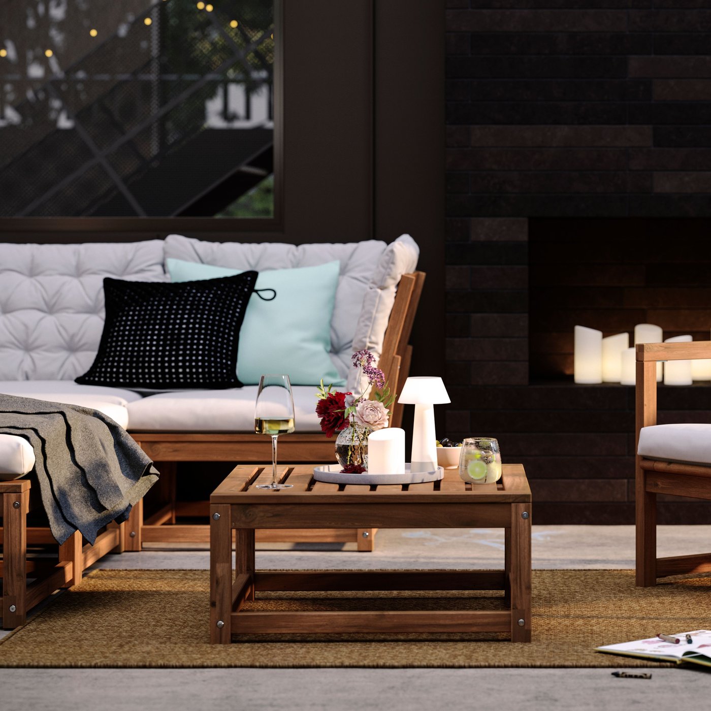 Une terrasse avec des sièges de salon NÄMMARÖ teintés brun clair et un élément d'assise pour un canapé modulaire pouvant également servir de table.