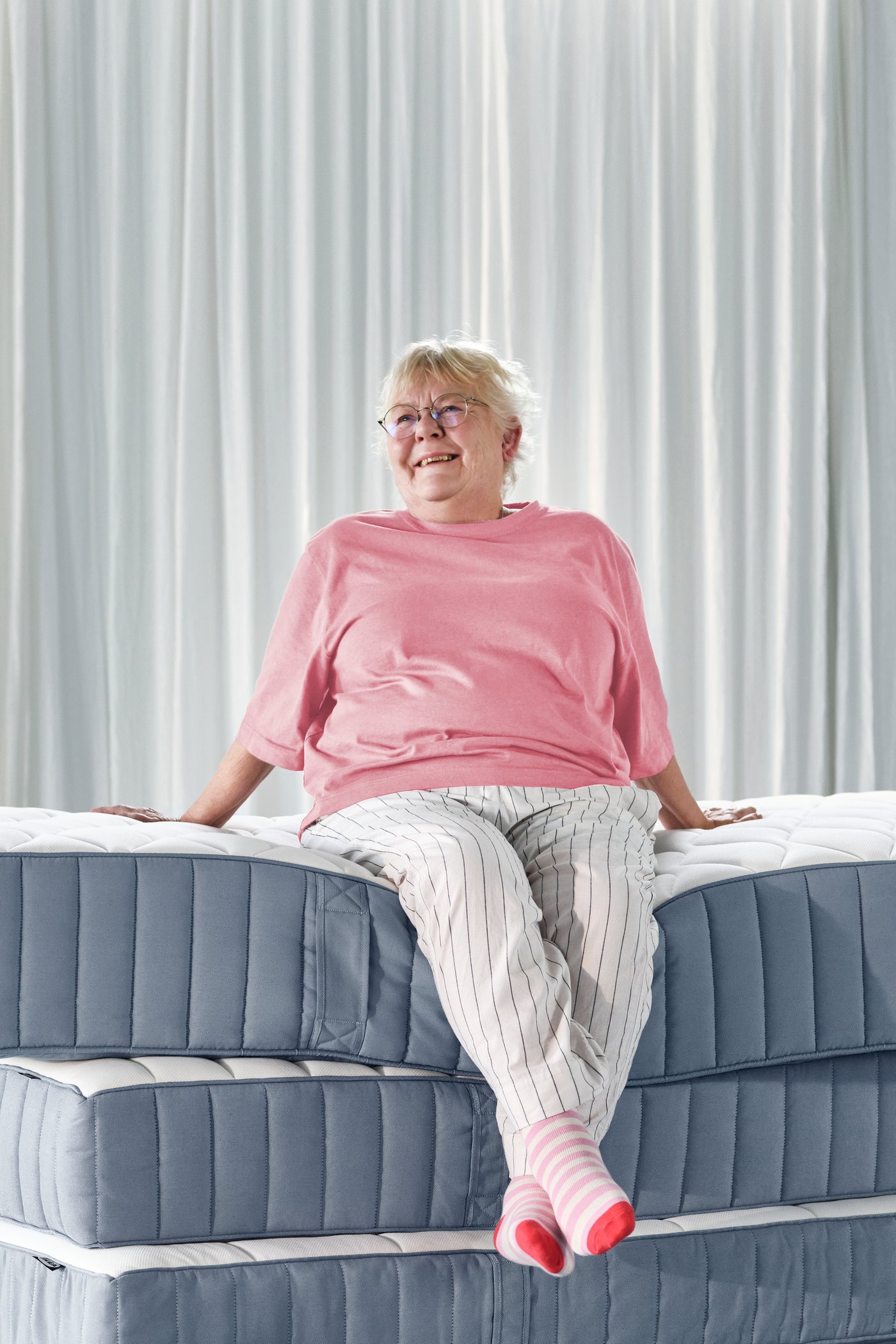 Eine Frau sitzt auf einem Stapel VÅGSTRANDA Federkern Matratzen.