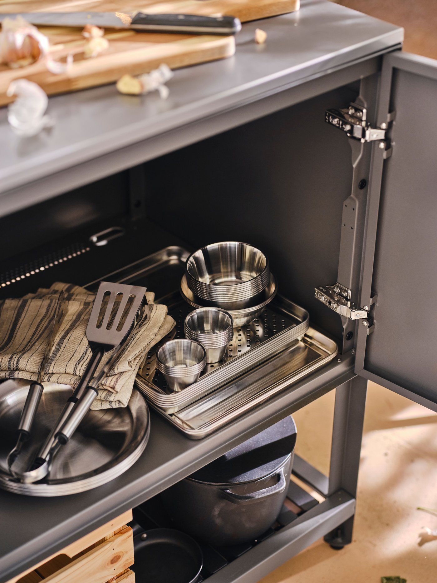 En mørkegrå BÅTSKÄR enhed med åbne låger med flere GRILLTIDER tallerkener, bakker, grillredskaber og skåle i.