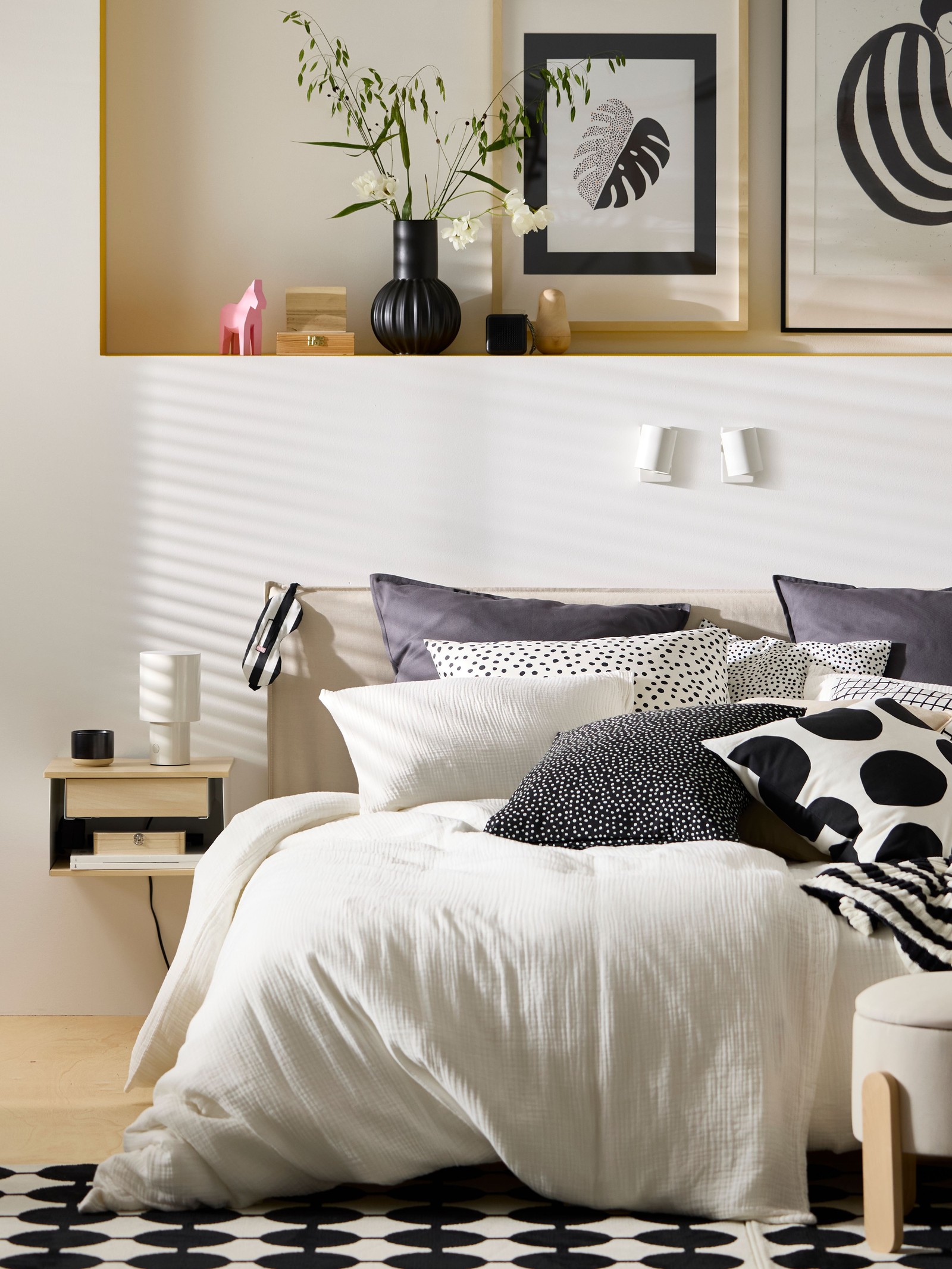 A large bed made up with lots of pillows and cushions as well as a white muslin SCHERSMIN duvet cover and pillowcase set.