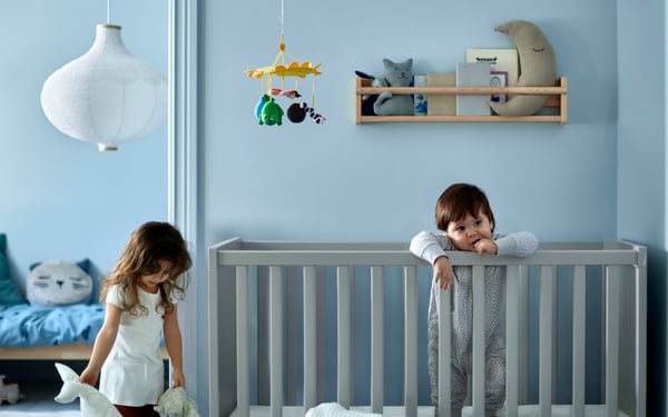 mama z niemowlakiem leżącym na łóżku pośród pościeli niemowlecej w paski niebiesko białe.