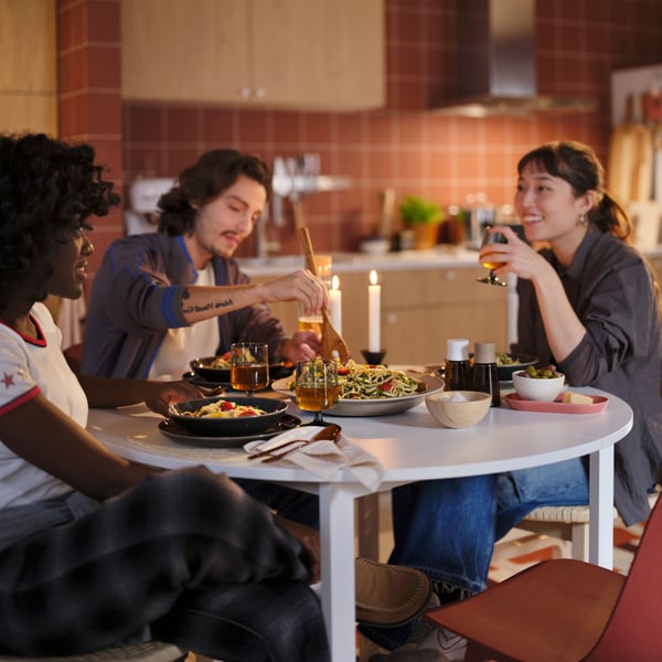 A group of friends enjoying a meal in a kitchen with red tiles.