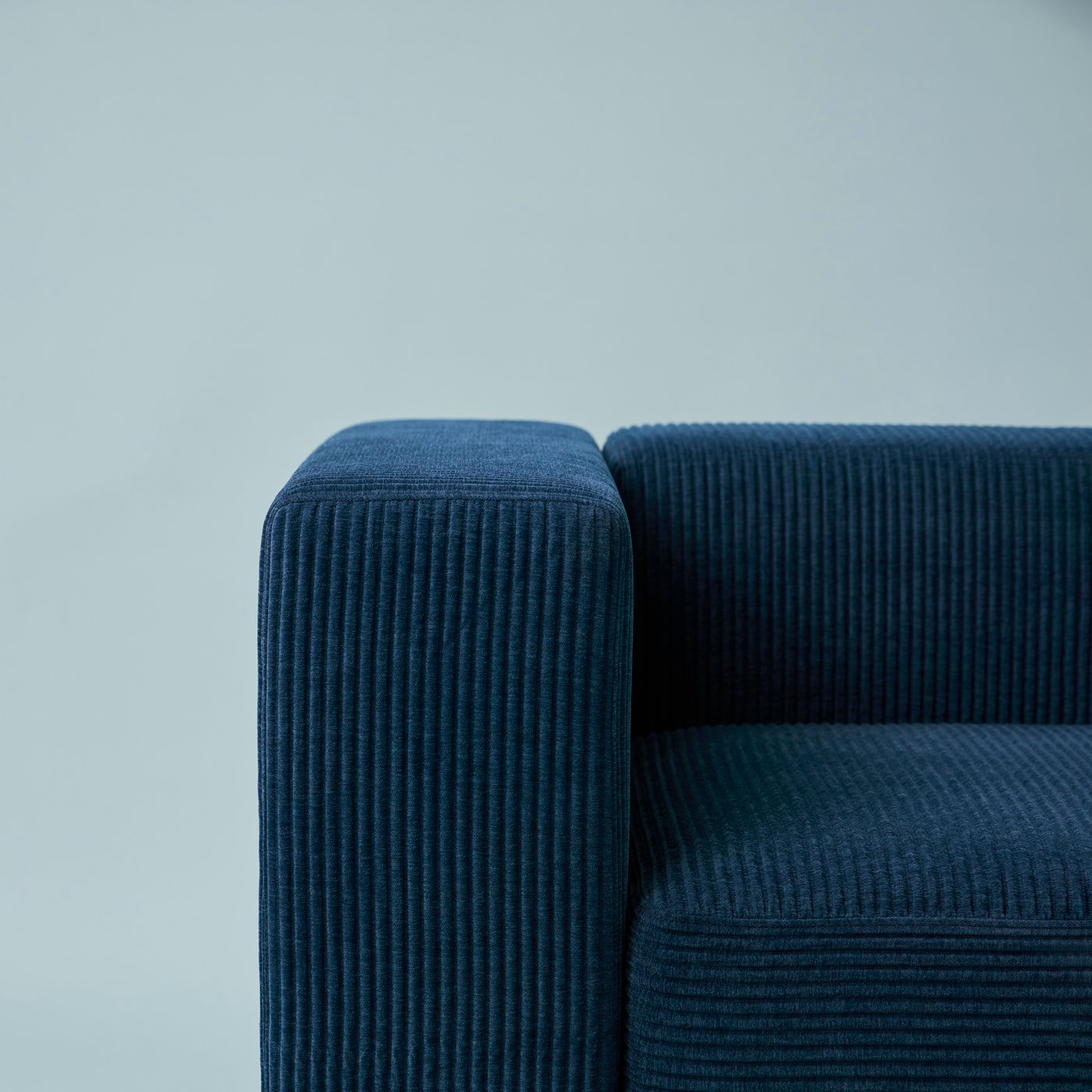 Part of a JÄTTEBO two-seat modular sofa in a Samsala dark-blue fabric against a light-blue background.