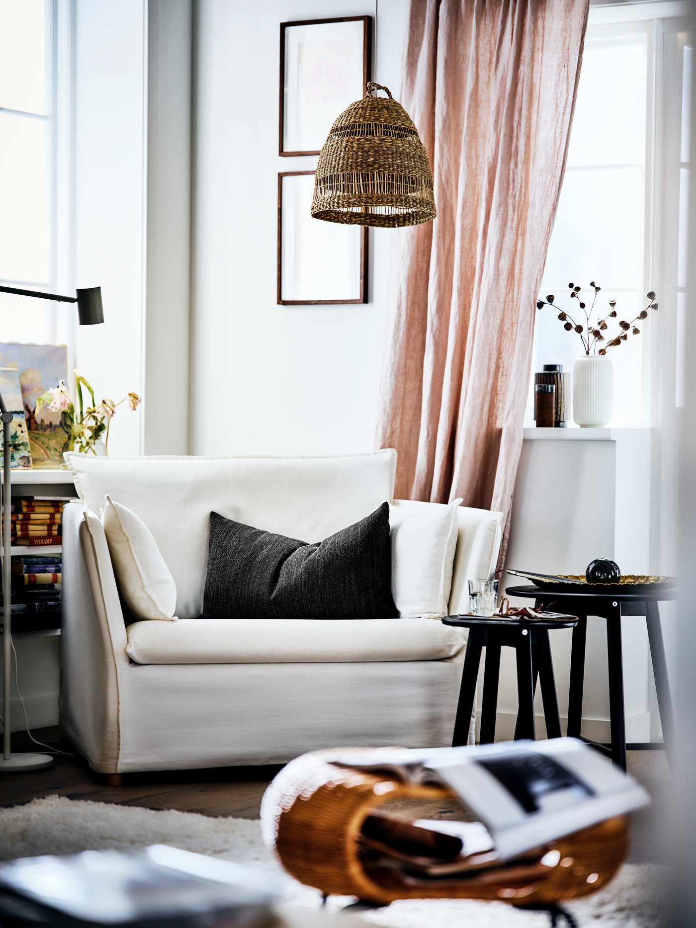 A BACKSÄLEN armchair in the corner of a bright living room with a pendant lamp overhead and a coffee table nest beside it.