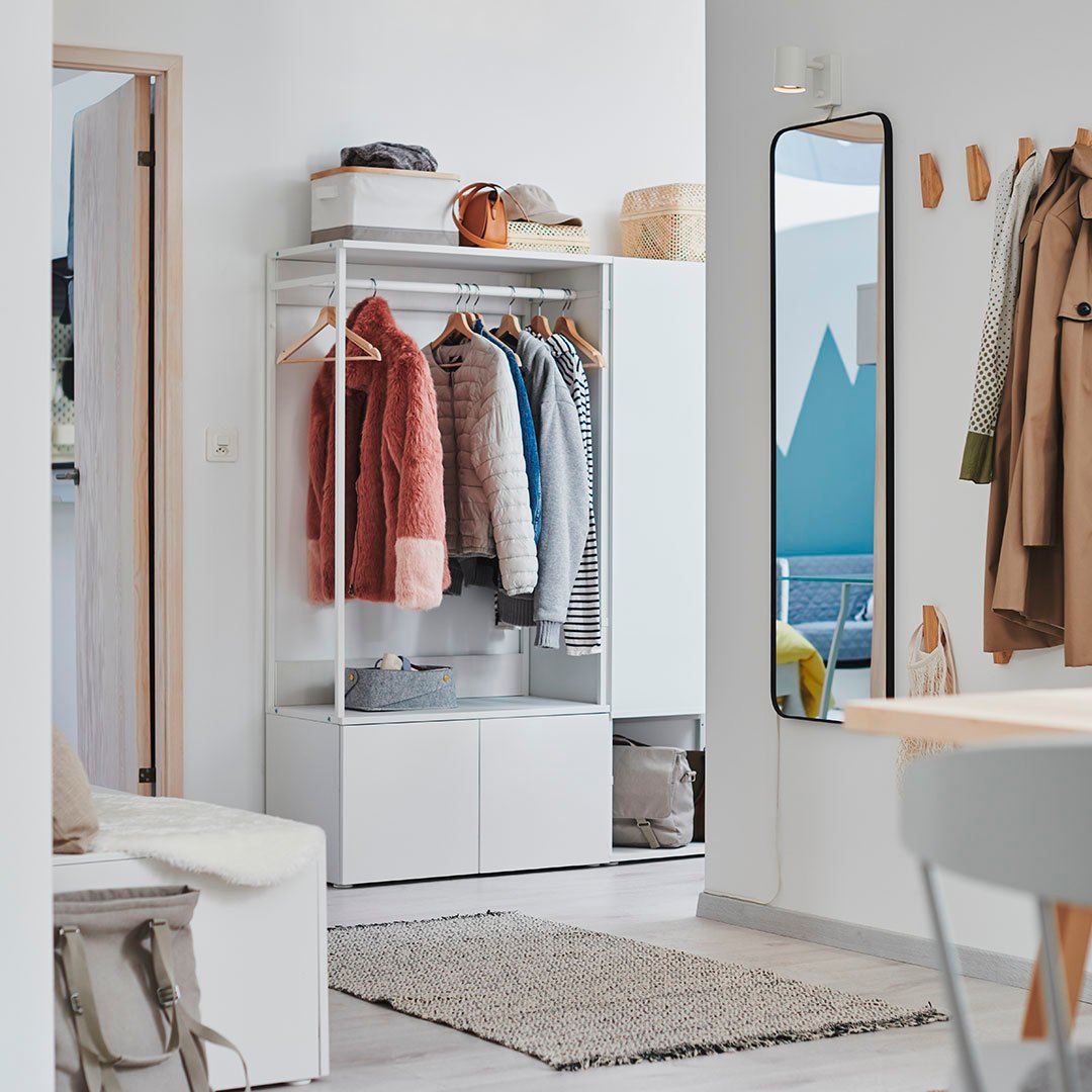 Stilren hall med PLATSA förvaring, spegel och krokar. Effektiv användning av utrymme med neutrala färger och färgglada detaljer från kläderna.