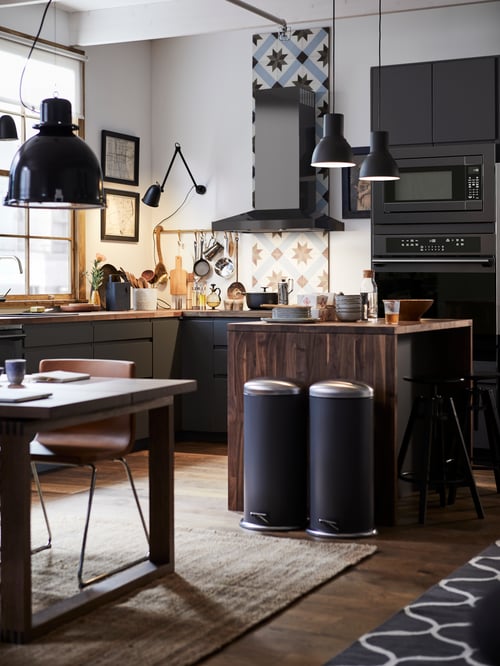 Kitchen with wooden base cabinet for sink with waste sorting space and 3 fronts, dining table and chairs on flatwoven rug. 