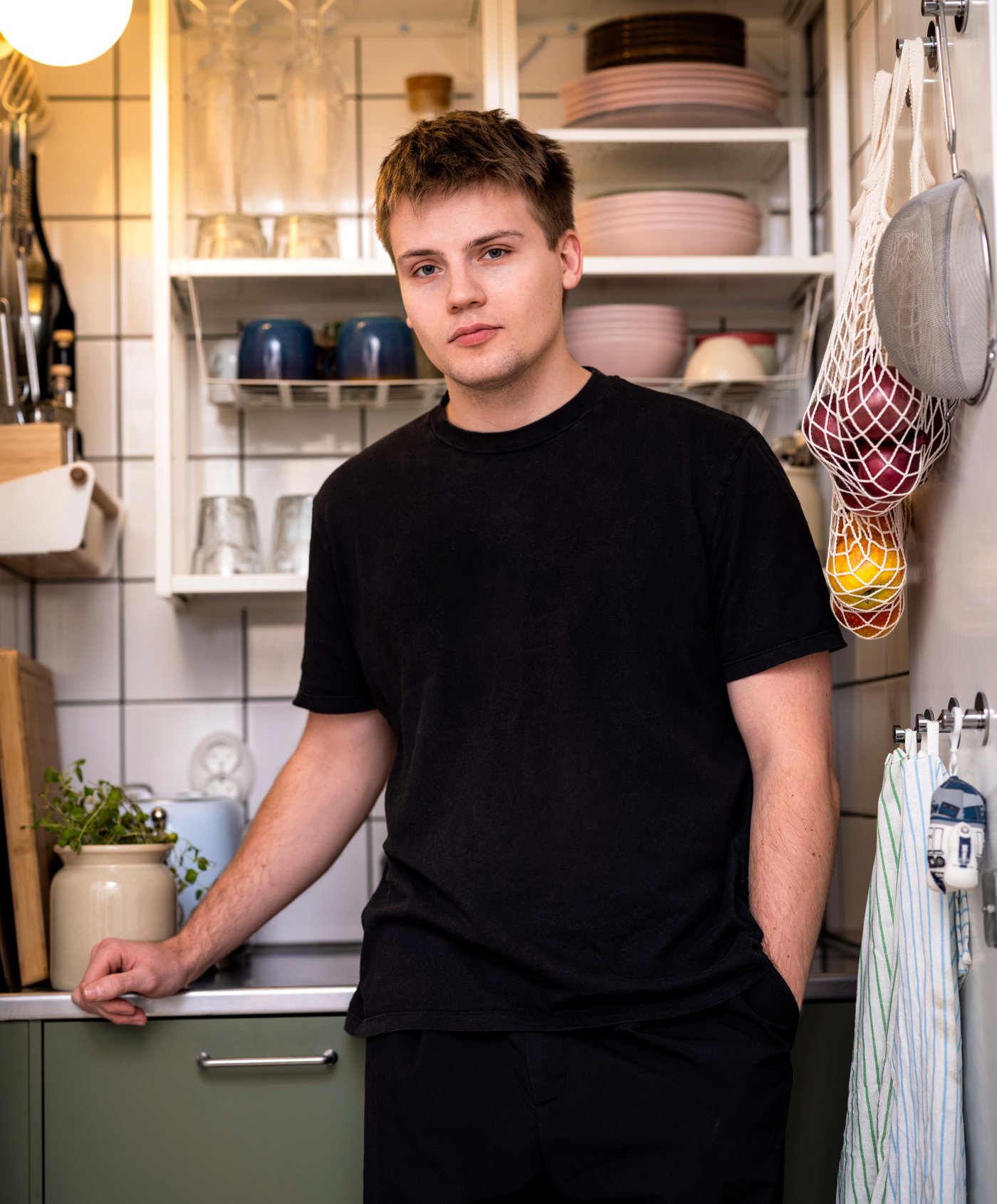 En man i svart t-shirt står i ett kök.