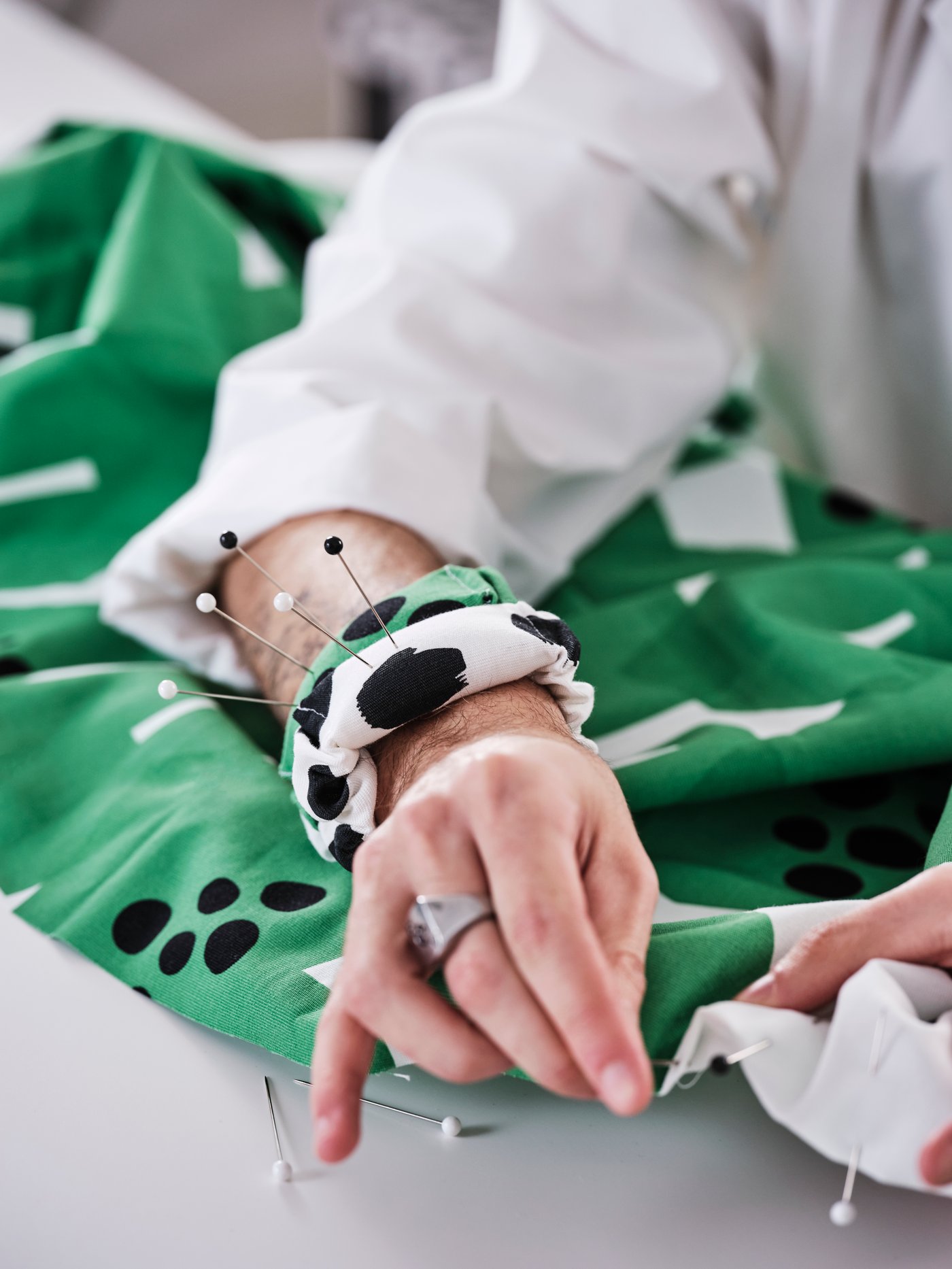 Hands are sticking pins into the ULLRANUNKEL pre-cut fabric. Bangles in the same fabric act as pincushions.