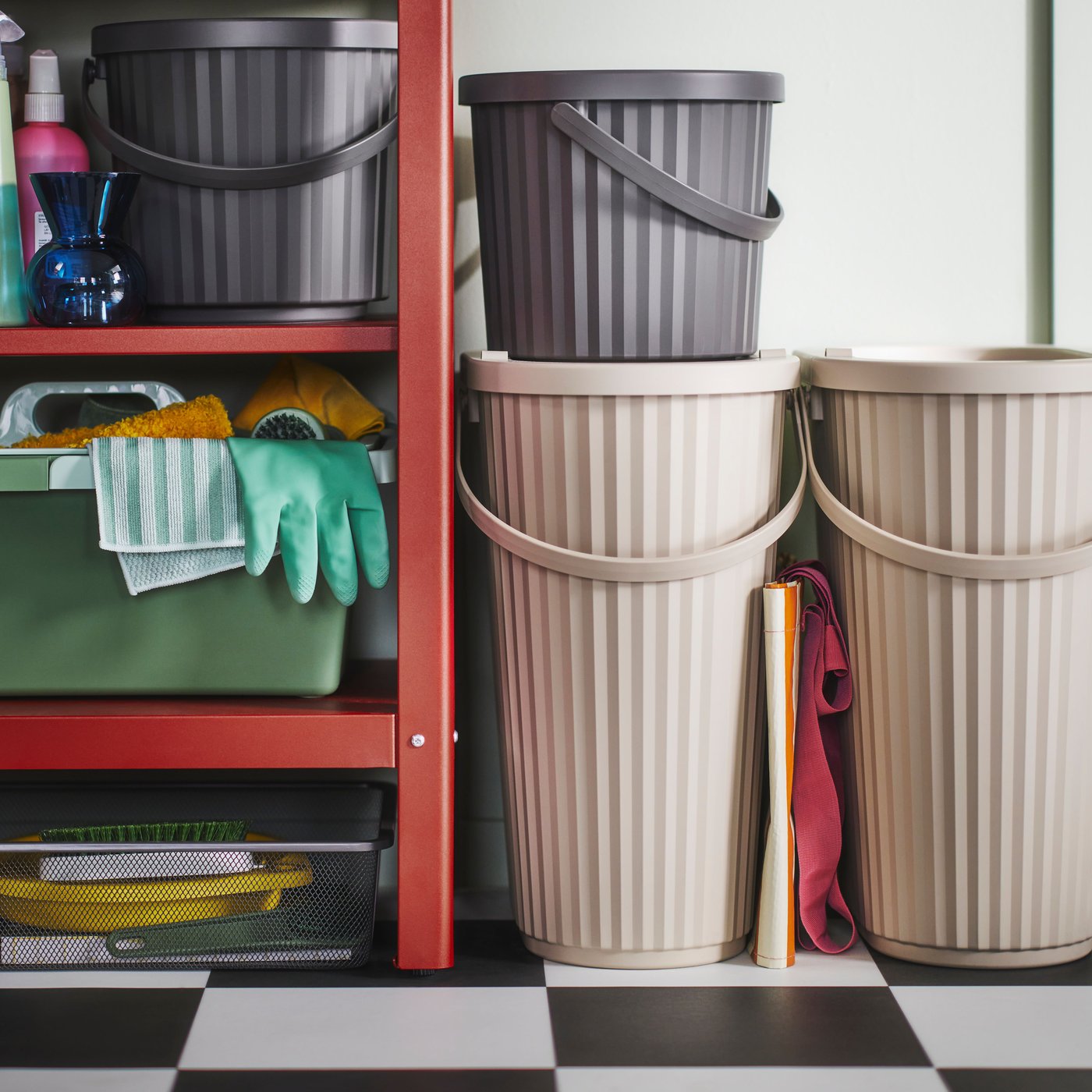 DAMMÄNG bins with lid of different sizes and colours stand on a black and white floor and on a shelf.