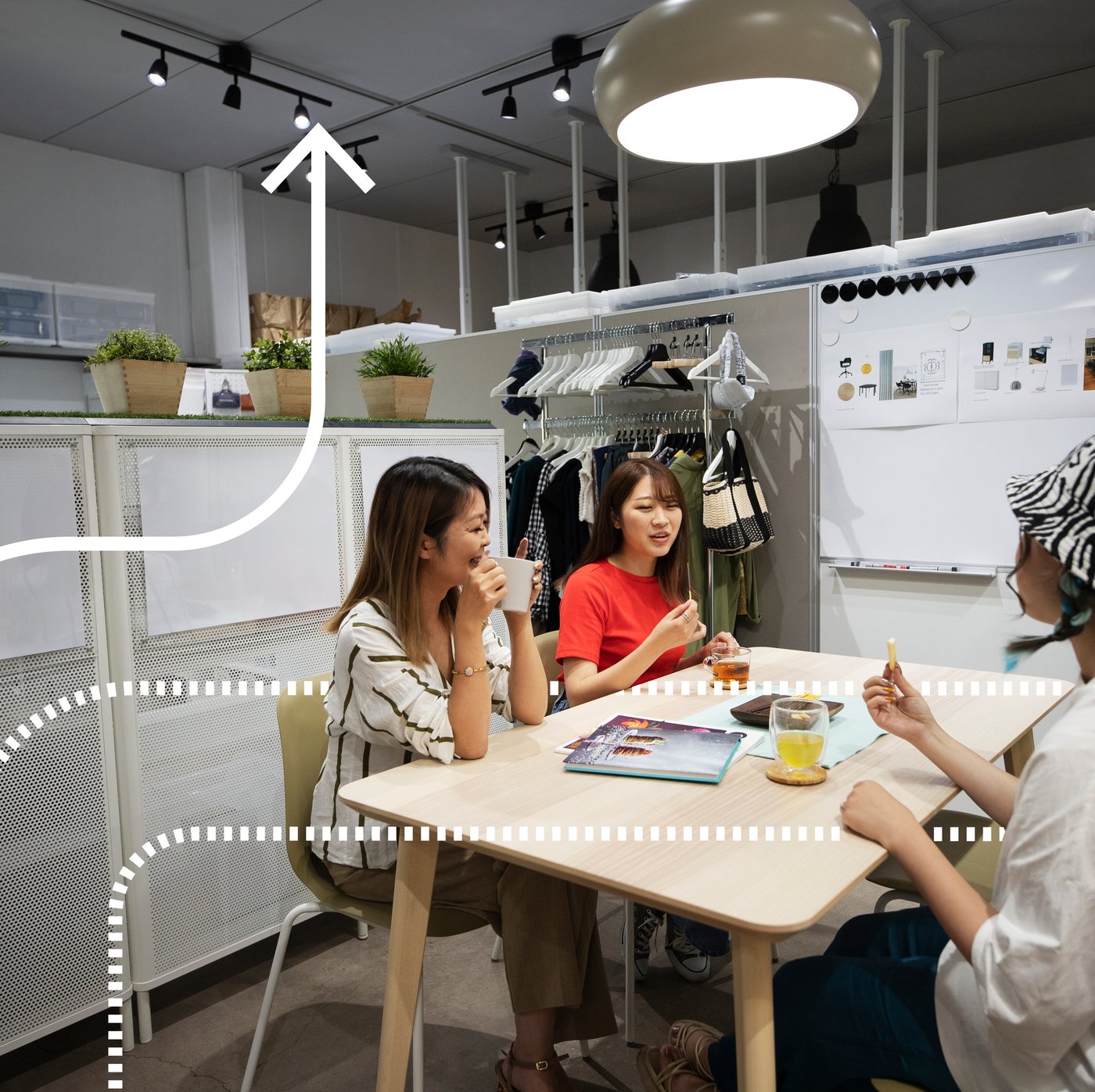 A man holding up a catalog of IKEA furniture is smiling at a table with others.