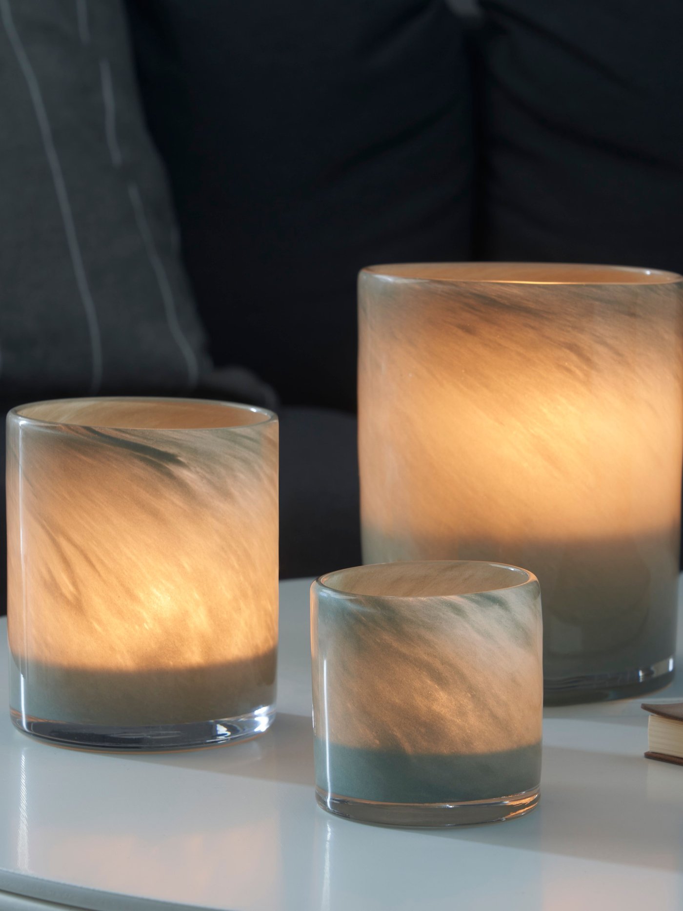 Tre VINDSTILLA ljushållare i olika storlekar står på ett bord.