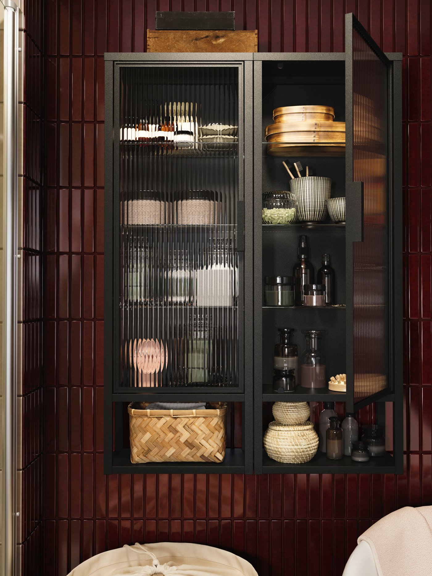 Ein MOSSJÖN Wandschrank mit Regalen und Glastüren, in dem Handtücher, Körbe und wichtige Dinge ordentlich angeordnet sind.