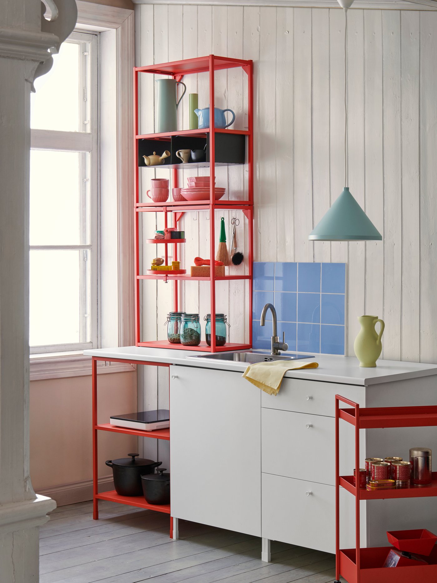 Beberapa modul ENHET berwarna merah jingga dan putih menyediakan storan terbuka dan tertutup dengan set makan malam yang berwarna-warni di dapur.
