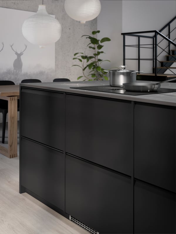 UPPLÖV anthracite kitchen fronts, with a FÖRDELAKTIG induction hob with integrated extractor and a HEMKOMST pot with lid.