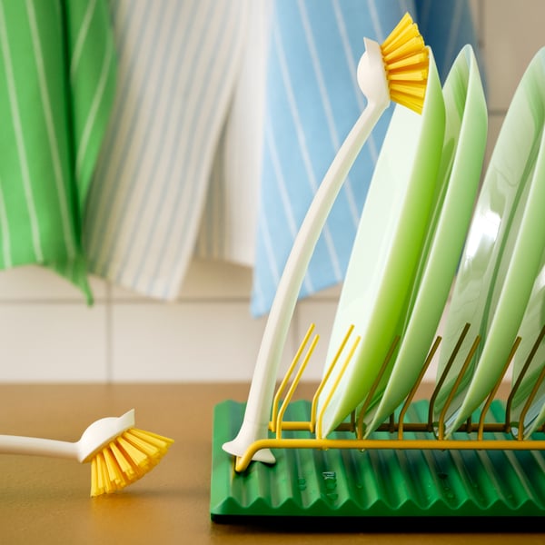 RINNIG dish-washing brush resting on a dish rack with plates drying in a kitchen.