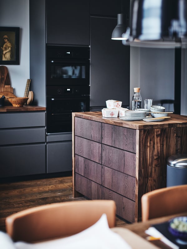 A METOD kitchen with a wooden kitchen island with plates and takeaway food containers on top.