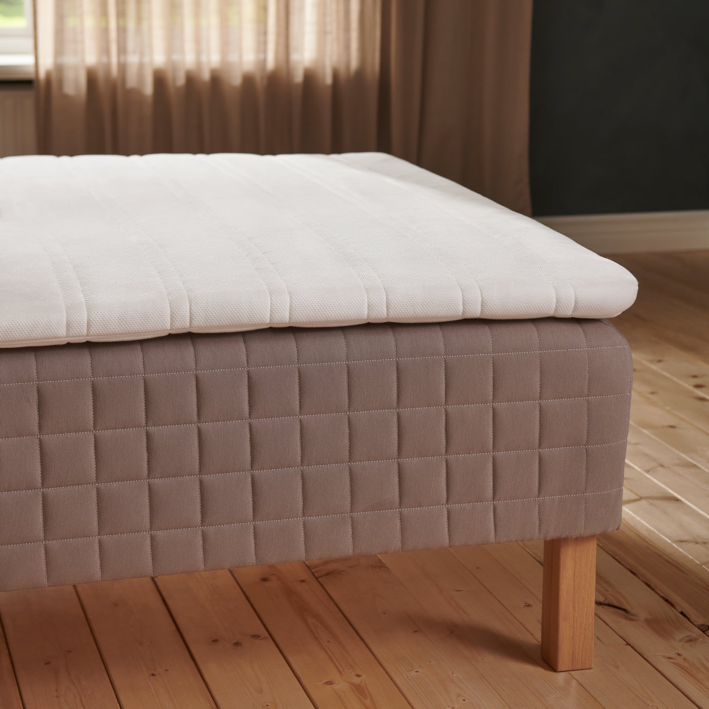 Puisella lattialla on tammisilla BURFJORD-jaloilla varustettu petaamaton SKÅRER-runkopatja, jonka päällä on sijauspatja.