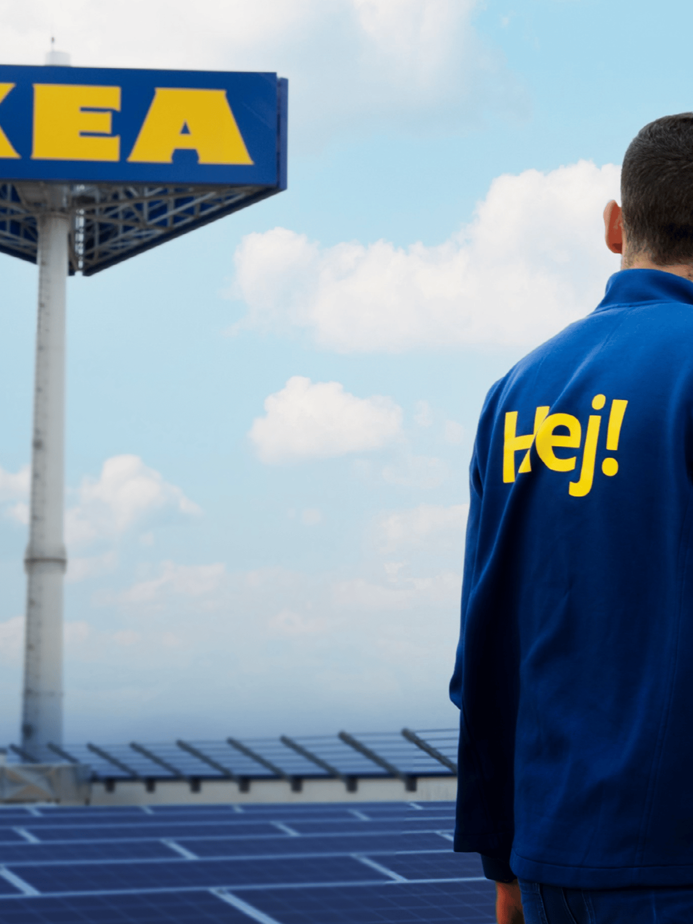 En mann med IKEA-uniform som står HEJ står utenfor IKEA varehus.