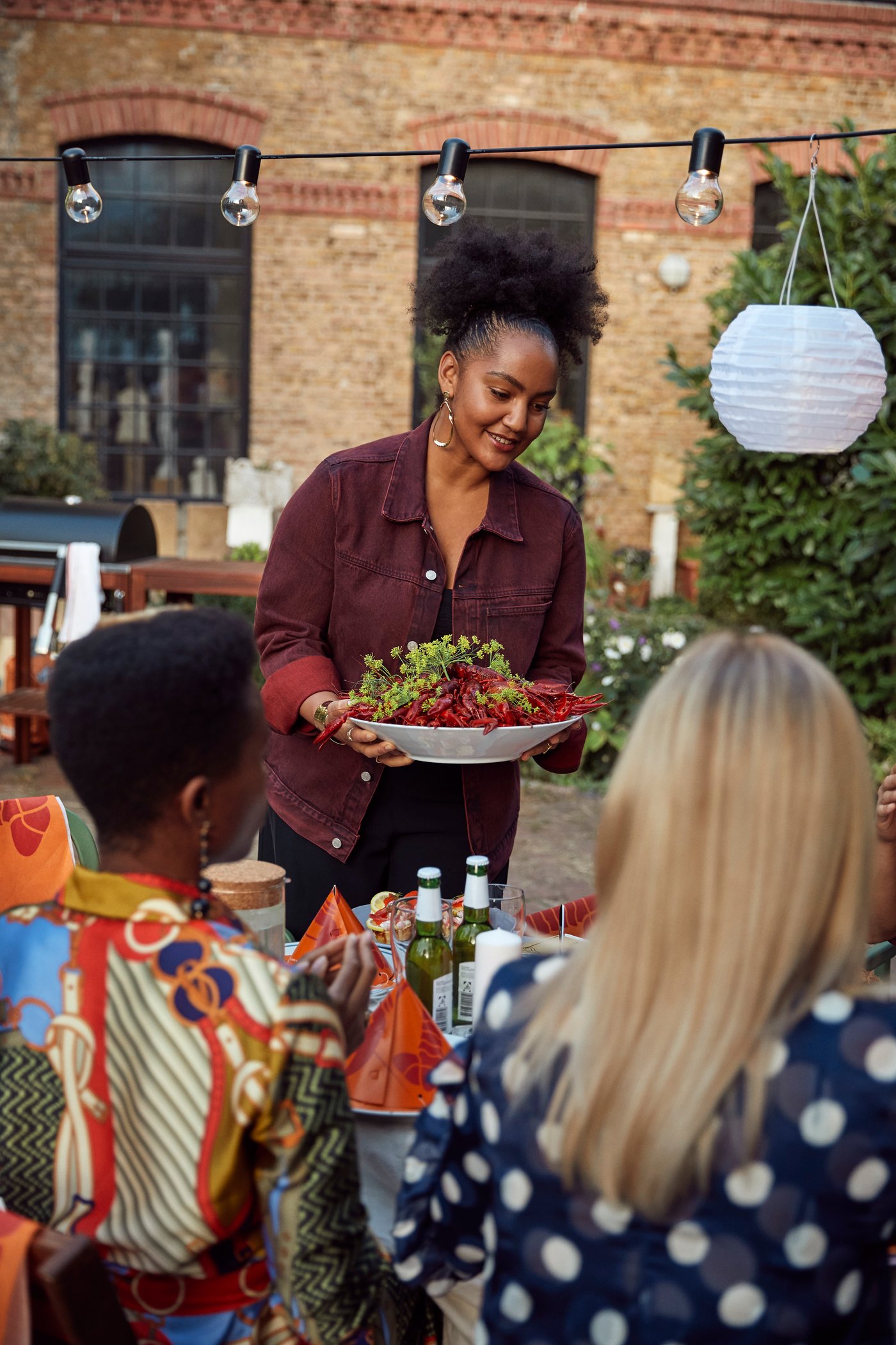 Eine Gruppe von Freunden sitzt in einem Hinterhof um einen Esstisch und geniesst das Krebsfest.