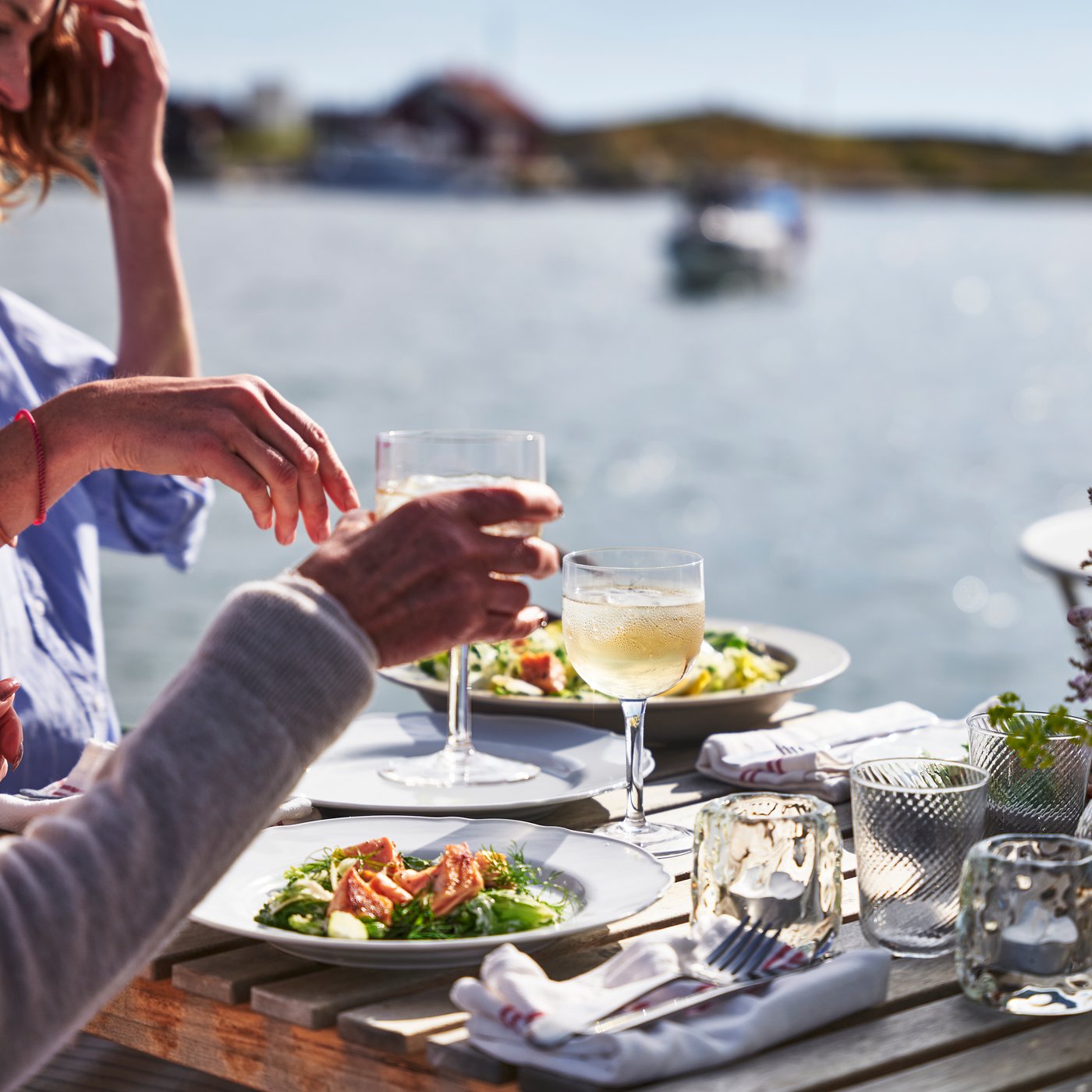 People are sitting at a table with wine glasses and plates with food in front of them.