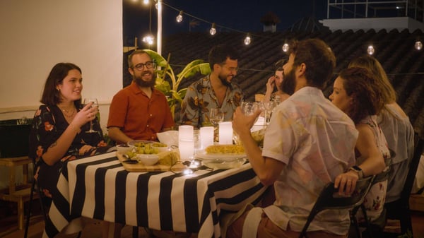 Group of friends on a balcony gathered around a table with food and drinks served.