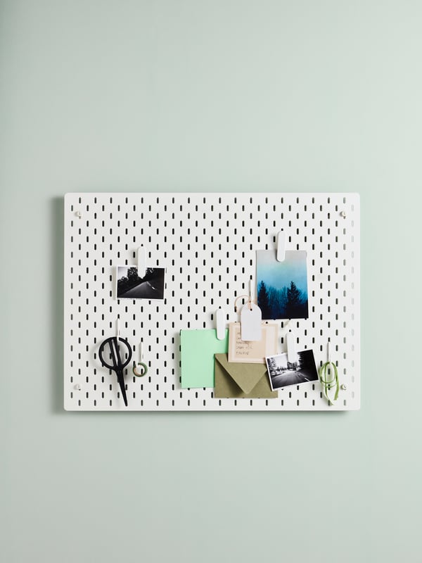 Una pared con un tablero de organización. En el tablero hay fotos colgadas, unos papeles y un lápiz.