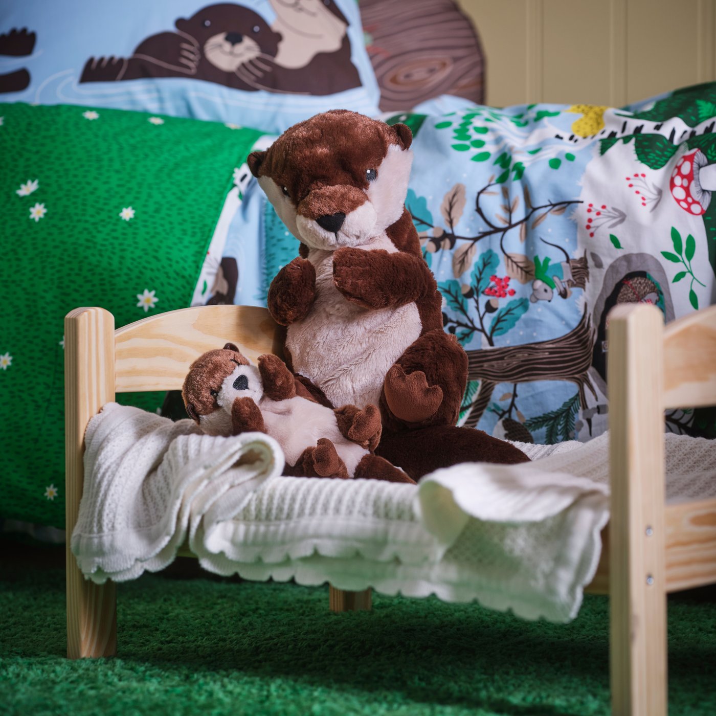 Due peluche SKOGSDUVA sopra un piccolo lettino per bambole DUKTIG. 