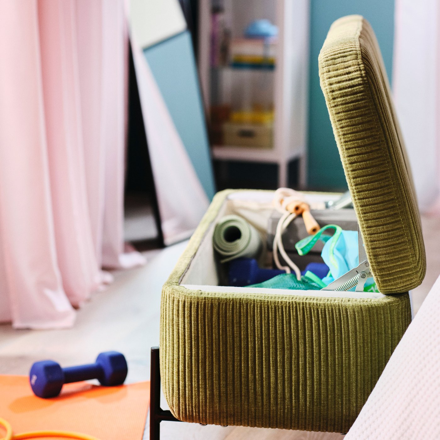 Ett rum med en grön VALTORP förvaringspall är öppen och visar yogamattor och sportutrustning inuti.
