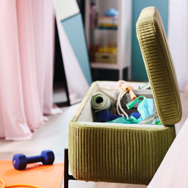 A room with a green VALTORP storage ottoman is open, showing yoga mats and sports equipment inside.