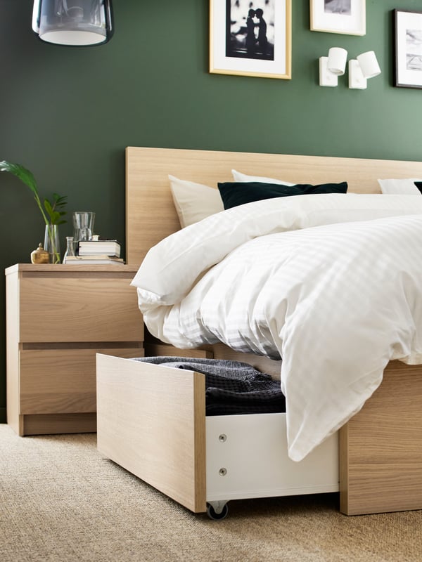 A birch MALM bed with a drawer partially pulled out.